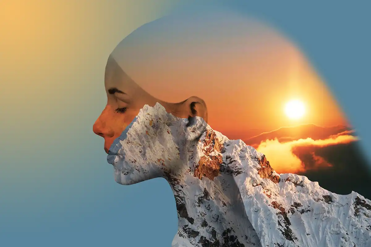 Composite of womans head exposing a sunset over mountains as the background.