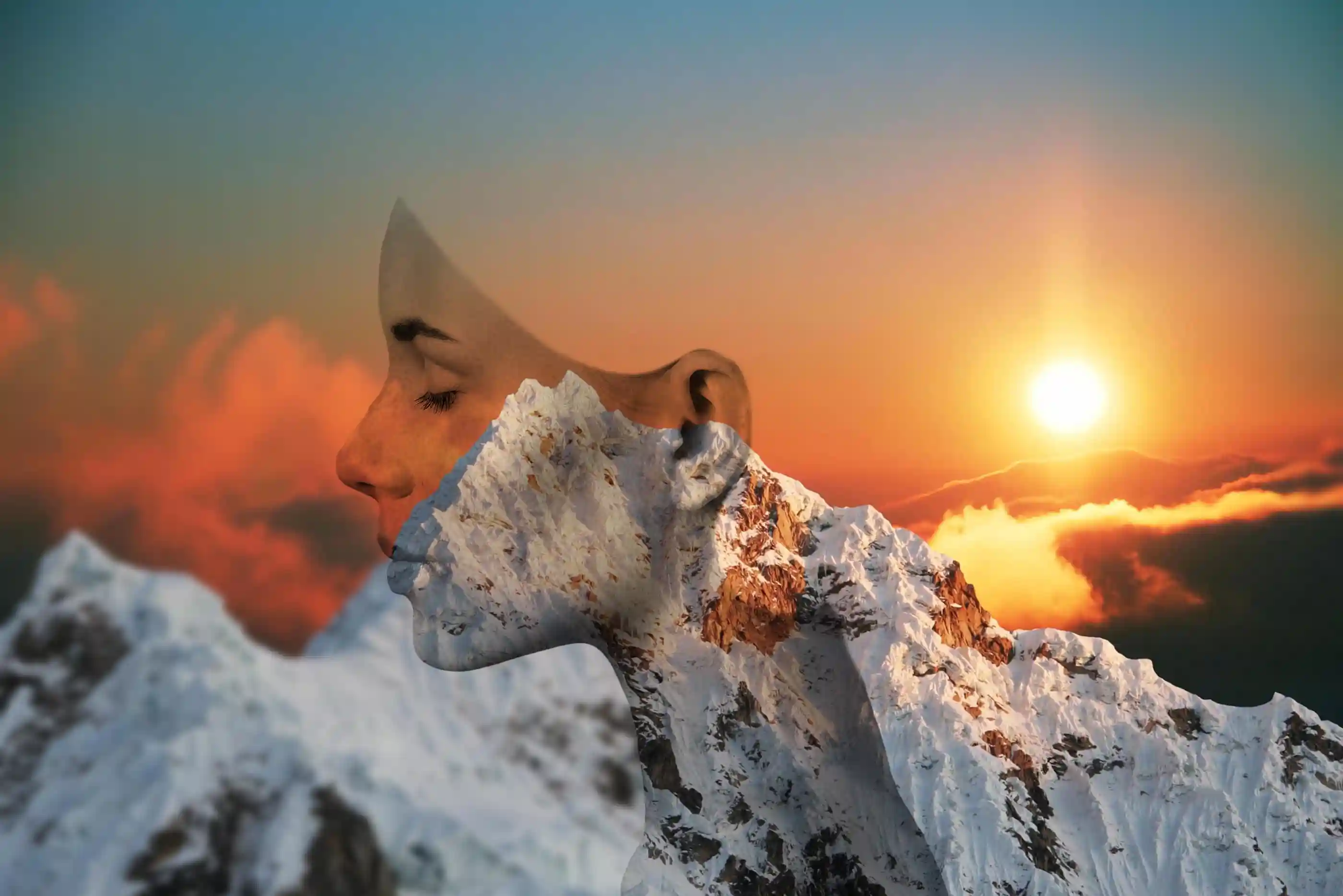 Composite of womans head mixed in with a sunset over mountains as the background.